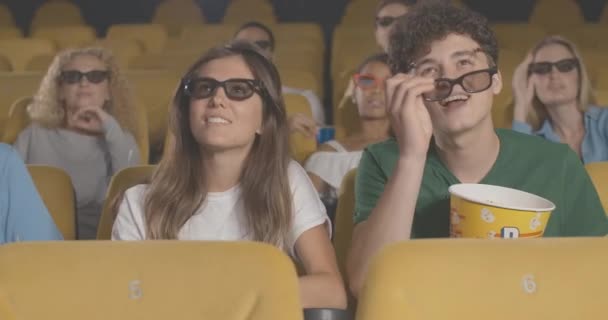 Porträtt av lyckliga unga par som diskuterar film på bio. Glada kaukasiska unga man och kvinna i 3D-glasögon titta på film och prata. Filmälskare dejtar inomhus. Bio 4k ProRes HQ. — Stockvideo