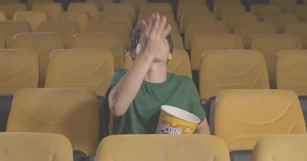 Porträtt av glad ung man i 3D-glasögon fånga popcorn med mun på bio. Avslappnad stilig vit besökare tittar på film i biografen och har roligt. Bio 4k ProRes HQ. — Stockvideo