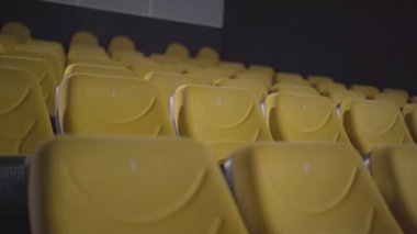 Kamera, sinema salonundaki sarı sandalyeler boyunca ilerler. Covid-19 salgını sırasında boş sinema salonu. Koronavirüs karantinasında sinema katılımının azalması.