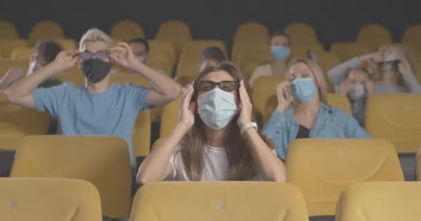Des gens masqués regardant des films en 3D au cinéma sur la quarantaine du coronavirus. Portrait d'hommes et de femmes au cinéma sur la pandémie de Covid-19. Style de vie verrouillé. Siège social Cinema 4k ProRes. — Video