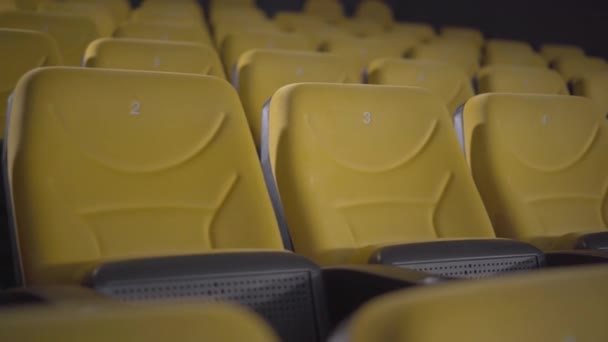 Puste, żółte kino bez ludzi na zamknięciu Covid-19. Kamera porusza się wzdłuż rzędu wygodnych foteli w kinie bez odwiedzających. Kwarantanna dla koronawiru. — Wideo stockowe