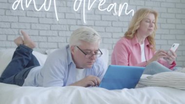 Gergin, orta yaşlı bir adam internetten karısını görmezden geliyor. Arka planda akıllı telefon kullanan üzgün bir kadın olarak video oyunları oynayan Kafkasyalı kıdemli oyuncunun portresi. Bağımlılık kavramı.