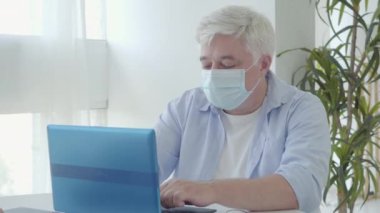 Covid-19 pandemik tecritte yüz maskeli kendinden emin bir adamın portresi. Coronavirus karantinasında çalışan orta yaşlı Kafkas işadamı. Uzak çalışma konsepti.