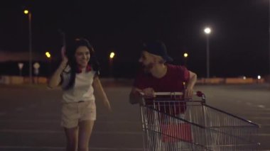 Mavi ve kırmızı ışıkta polisten kaçan komik genç çift. Alacakaranlıkta boş otoparkta tramvayla gülen ve koşan neşeli beyaz kadın ve erkek portresi. Gece gençliği eğlencesi.