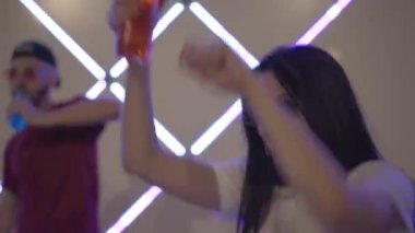 Rahatlamış kadın neon ışıklarda dans ediyor ve gece kulübünde arka planda bulanık erkek dansı gibi bira içiyor. Olumlu milenyum insanları alkol ve müzikle parti yapıyor.