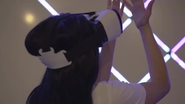 Vue de face arrière de la femme joyeuse excitée dans VR-lunettes debout dans les néons et les mains en mouvement. Jeune joueuse caucasienne profitant de la réalité virtuelle dans VR-club. Jeux modernes de réalité augmentée. — Video