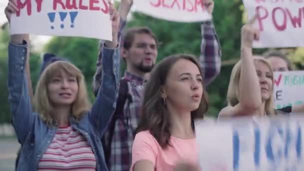 Şehir sokaklarında bağıran afişlerle bir grup beyaz protestocu. Açık havada cinsiyet ayrımcılığına karşı bir gösteri. Kızgın erkek ve kadın göstericiler kadın haklarını savunan pankartlarla. — Stok video