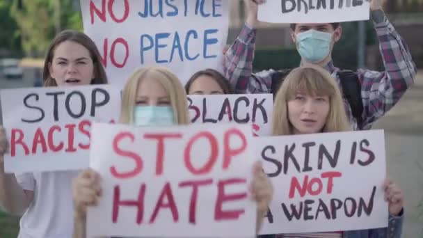 Een groep serieuze mensen die demonstreren tegen discriminatie. Portret van blanke demonstranten met spandoeken en geschreeuw over mensenrechten. Rellen tegen racisme in de democratie. — Stockvideo