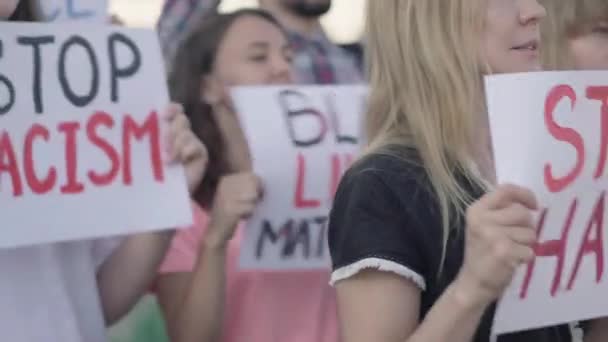 Zijaanzicht van activisten menigte met anti-racisme spandoeken schreeuwen. Een groep demonstranten die vecht tegen etnische ongelijkheid. Demonstranten die de mensenrechten in maart beschermen tegen vooroordelen. — Stockvideo