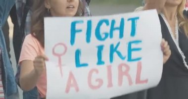 Canlı kamera, grevde olan feminizm pankartlı bir kalabalık. Cinsiyetçilik karşıtı posterleri olan beyaz erkek ve kadın portresi bağırıyor ve pankartları sallıyor. Kadın hakları ayaklanması. Sinema 4k ProRes Merkezi.