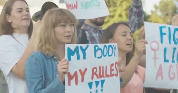 Довірливі молоді активісти протестують проти гендерної дискримінації та нерівності. Портрет кавказьких жінок і чоловіків з антисексистськими плакатами, які кричали і жестикулювали. Фільм 4k ProRes HQ. — стокове відео
