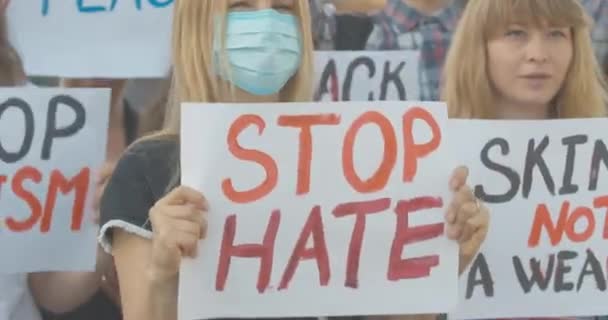 Een menigte activisten protesteert tegen sociale ongelijkheid over de Covid-19 pandemie. Blanke mensen met Stop haat en anti-racisme spandoeken schreeuwen op protest tegen discriminatie. Cinema 4k ProRes Hoofdkwartier. — Stockvideo
