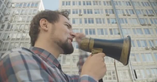 Side view close-up van boze man schreeuwen door megafoon en gebaren. Portret van een blanke demonstrant die demonstraties in de stad aanmoedigt. Opstand voor de mensenrechten. Cinema 4k ProRes Hoofdkwartier. — Stockvideo