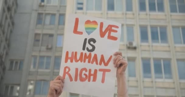 Ręce z flagami LGBT podnoszącymi się w miejskim mieście. Nierozpoznani kaukascy demonstranci na paradzie gejowskiej dumy trzymający slogany na rzecz równości orientacji seksualnej. Kino 4k ProRes kwatera główna. — Wideo stockowe