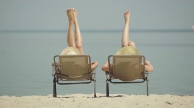 Yazlık tatil köyünde bronzlaşmış ince bacakları sallayan Kafkas kadınlarının arkası. Tanınmayan genç turistler güneşlenip güneşleniyorlar. Mutlu varlıklı arkadaşlar tatilin tadını çıkarın.