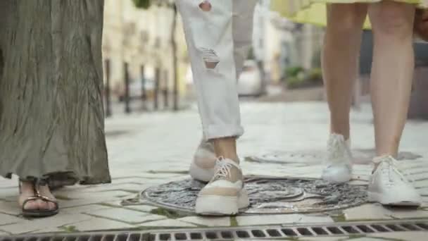 Tre paia di piedi camminando lungo il marciapiede in città nella giornata di sole. Donne caucasiche irriconoscibili che passeggiano all'aperto nei fine settimana estivi. I turisti che riposano all'estero in Europa. — Video Stock