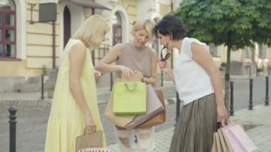 Çekici, neşeli bir kadın Summer City caddesinde arkadaşlarına alışveriş yapıyor. Alışveriş torbalarıyla övünen mutlu orta yaşlı beyaz kadın portresi. Alışverişte yaşam tarzı, Kara Cuma konsepti..