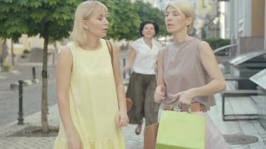 Neşeli orta yaşlı bir kadın Summer City caddesinde bekleyen arkadaşlarına koşuyor ve onları yanaklarından öpüyor. Kendine güvenen beyaz kadınlar selamlaşıp gidiyor. Kadın arkadaşlığı, yaşam tarzı..