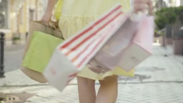 Cámara sigue feliz mediados de adulto hermosa mujer caminando y girando con bolsas de compras en la calle de la ciudad de verano. Positiva rica dama caucásica girando y sonriendo a la cámara el viernes negro día de las ventas. — Vídeo de stock