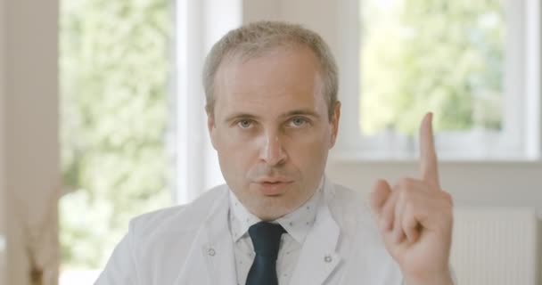Detailní záběr sebevědomého vážného lékaře, jak zvedá prst a mluví. Portrét profesionálního lékaře, který vysvětluje virové nebezpečí před kamerou na Covid-19 pandemii. Cinema 4k ProRes HQ. — Stock video