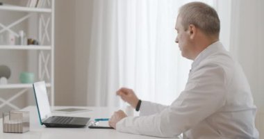 Doktor reklam kavanozunun yan görüntüsü ve dizüstü bilgisayarlı fotoğraf makinesinde haplar. Covid-19 salgınında sanal konferansta tedaviyi tartışan profesyonel bilim adamının portresi. Sinema 4k ProRes Merkezi.