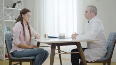 Hastanedeki kadından rüşvet almayı reddeden orta yaşlı bir doktor. Profesyonel erkek doktorun kadın hastaya para yedirme portresi. Tıbbi yolsuzluğa karşı dürüst beyaz adam.