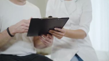 Tanımlanamayan kadın doktor, erkek hastaya belge veriyor. Genç beyaz kadın deneysel tedaviye hasta adamın rızasını alıyor. Sağlık ve Tıp Konsepti.