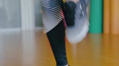 Kamera, içeride antrenman yapan güçlü atletik kadın vücudunda hareket ediyor. Spor salonunda egzersiz yapan kendine güvenen beyaz kadın portresi. Yüksek dizli koşucu bayan sporcusu.