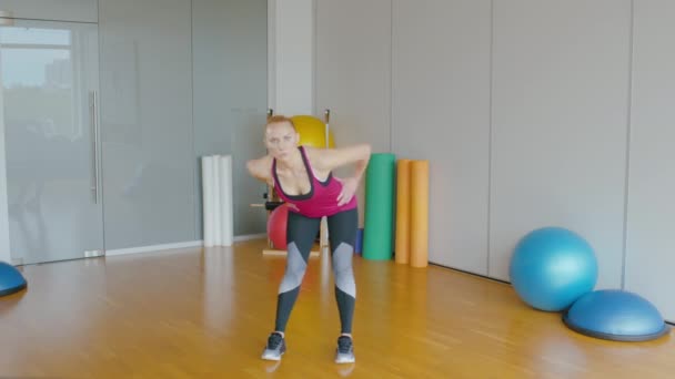 Vue d'ensemble de l'entraîneur sportif professionnel montrant l'exercice et de parler. Portrait d'une femme blanche confiante qui entraîne des gens au gymnase. Femme aux cheveux roux sportive s'entraînant à l'intérieur. Mode de vie sain. — Video