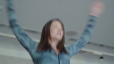 Zıplayan ve el kaldıran sporcu kadının alt görüntüsü. Spor salonunda ya da evde antrenman yapan kendine güvenen ince, beyaz bir kadının portresi. Sağlıklı yaşam tarzı ve uygunluğu.