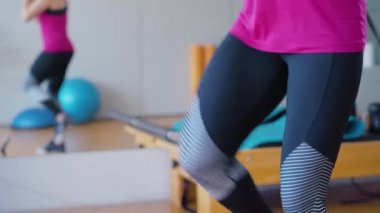 Spor salonunda bacaklarını kaldıran tanınmamış sporcu kadın. Spor giyinen beyaz kadın içeride spor yapıyor, atletik kadın çalıştırıyor..