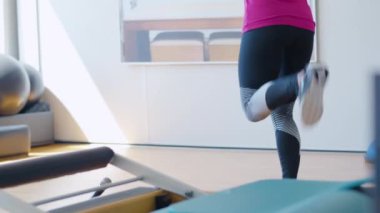 Sporcu kadının arka açıdan bacak kaslarını içeride çalıştırması. Spor salonunda ayağını kaldıran tanınmayacak kadar zayıf atletik bir kadın. Spor yapan bayan..