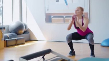 Güneşli bir günde spor salonunda sporcu kadın antrenmanına odaklan. İçerde çömelmiş, kendine güvenen beyaz kadın portresi. Genç atletik bayanın antrenmanı..