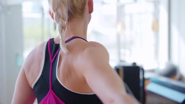 Achteraanzicht close-up van onherkenbare vrouw die hand- en schouderspieren traint. Fit blanke sportvrouw doet oefeningen binnen. Blond jong dame oefenen in de sportschool. — Stockvideo