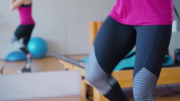 Desportista irreconhecível a levantar pernas no ginásio. Mulher caucasiana esportiva em sportswear treinamento dentro de casa, Exercício de senhora atlética. — Vídeo de Stock