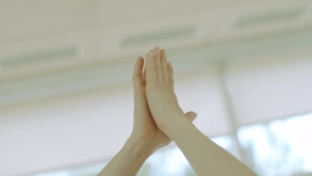 Câmera segue as mãos femininas caucasianas movendo-se para baixo em gesto de ioga. Retrato de jovem yogi feminino praticando dentro de casa. Bela confiante morena esportista formação em ginásio. — Vídeo de Stock