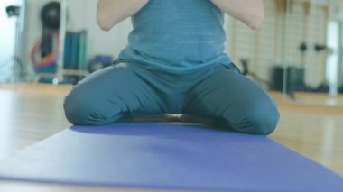 Egzersiz minderinde yoga yapan orta yaşlı beyaz adamın portresi. Spor salonunda kendine güveni tam, beyaz saçlı erkek yogi antrenmanı. Yaşlanmış sporcunun sağlıklı yaşam tarzı. Farkındalık ve zihin gücü kavramı.