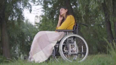 Tekerlekli sandalyedeki depresif genç kadının yaz akşamını parkta yalnız geçirmesi. Gün batımında dinlenen güzel beyaz engelli kadın portresi. Yalnızlık ve umutsuzluk..