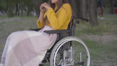 Parkta tekerlekli sandalyede oturan, tanınmayan, belden aşağısı felçli bir kadın. Kafkasyalı engelli insan yaz akşamını dışarıda yalnız geçiriyor. Özürlülük ve yalnızlık.