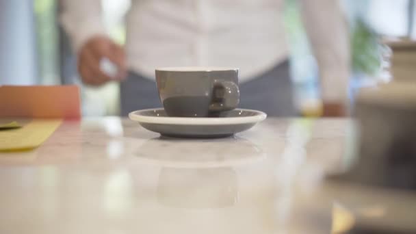 Primer plano de la taza de café de pie en la cafetería como hombre borroso tomando bebida y salir. irreconocible confidente caucásico hombre de negocios tener descanso. — Vídeo de stock