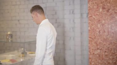 Esmer genç adam kahve fincanını tezgahtan alıp içiyor. Kendine güvenen beyaz bir adamın ara verdiğinin yan görüntüsü. Başarılı iş adamı öğle yemeğinde dinleniyor..