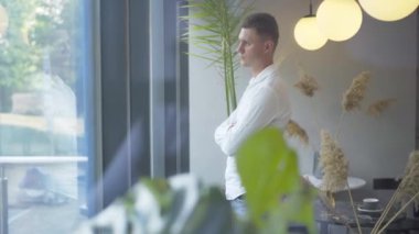 Kafede duran düşünceli genç bir adamın penceresinin arkasında ateş etmek. Kafkasyalı iş adamının restoranda iş görüşmesi için beklemesinin yan görüntüsü. Girişimcilik kavramı.