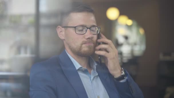 Seriöser Geschäftsmann legt Telefon auf und spricht mit jemandem. Porträt eines selbstbewussten erfolgreichen Mannes mit Brille bei einem Geschäftstreffen im Café. Erfolgskonzept. — Stockvideo