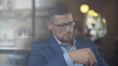 Ciddi bir iş adamı cam pencerenin arkasından telefona cevap veriyor. Gözlüklü, restoran işleriyle uğraşan kendine güvenen beyaz adamın yakın plan portresi. Başarılı bir yaşam tarzı.