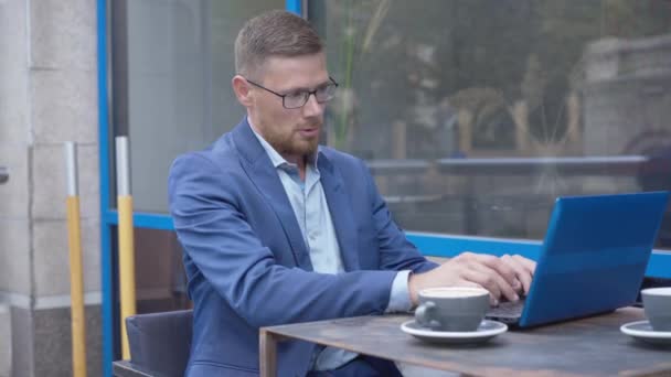 Porträtt av överarbetade kaukasiska affärsman surfa på Internet på bärbar dator. Trött stilig man som tar av sig glasögon, suckar och gnuggar ögon. Affärer och stress. — Stockvideo