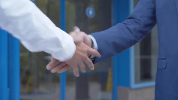 Poignée de main rapprochée d'un homme d'affaires prospère et d'un superviseur de bâtiment devant le centre d'affaires. Entrepreneur caucasien méconnaissable et travailleur avec des paumes de travail serrant la main à l'extérieur. — Video