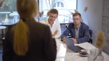 Masada oturan odaklanmış işadamları genç bir kadının konuşmalarını ve el kol hareketlerini dinliyorlar. Kafe 'deki ortaklara veya meslektaşlara girişimi açıklayan tanınmamış beyaz iş kadını.
