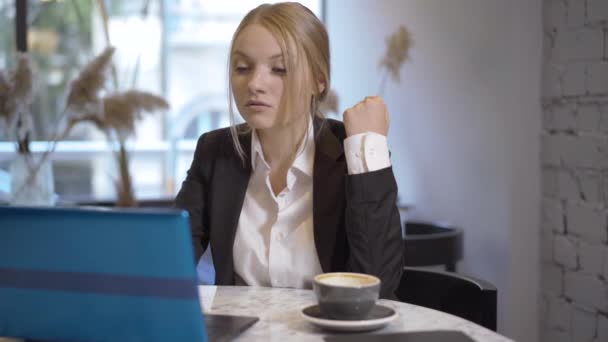 成功的年轻女商人的咖啡休息时间。自信全神贯注的女人坐在餐桌旁，坐在咖啡厅里，用笔记本电脑上网。漂亮的黑发女士工作过度. — 图库视频影像