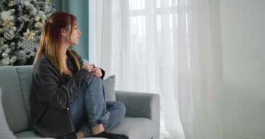 Depresyonda olan genç bir kadının Noel 'i evde yalnız geçirmesi. Arka planda Yeni Yıl ağacı olan muhteşem beyaz kadın portresi. Sinema 4k ProRes Merkezi.