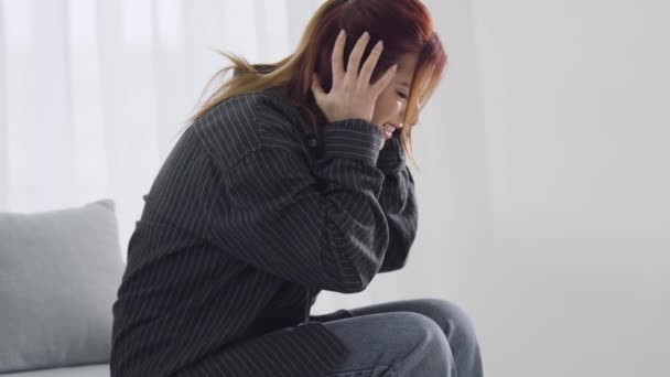 Side view van gestresste jonge vrouw met ernstige migraine. Mooie roodharige blanke dame met hoofdpijn. Symptomen van posttraumatische stressstoornis. Gezondheidszorg en geneeskunde. — Stockvideo